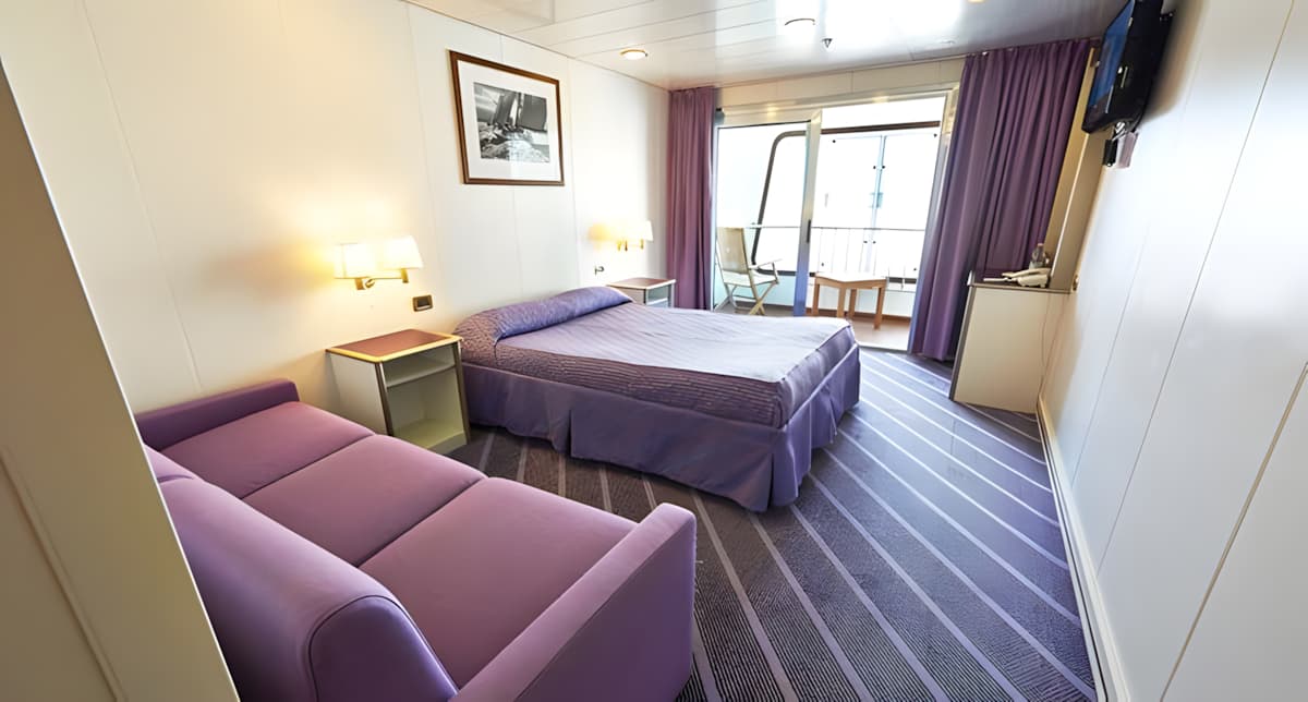 Une cabine luxueuse sur un des navires de Corsica Ferries avec un lit double, un canapé et même un balcon