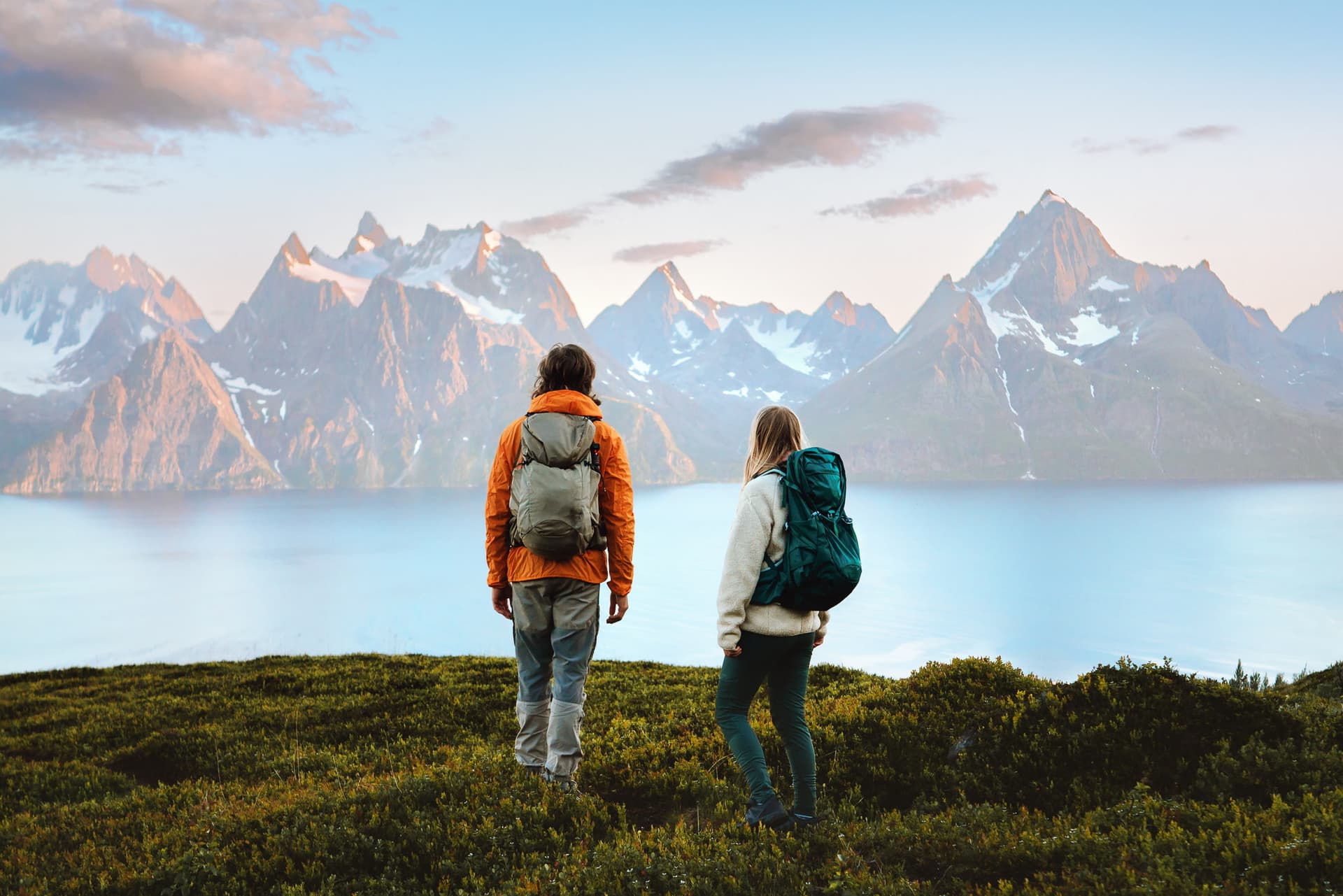 Un couple profitant du paysage montagneux en Norvège, des amis, un homme et une femme, randonnée avec sac à dos, vacances actives, mode de vie sain, famille d'aventuriers en plein air, à la découverte des sentiers des Alpes de Lyngen