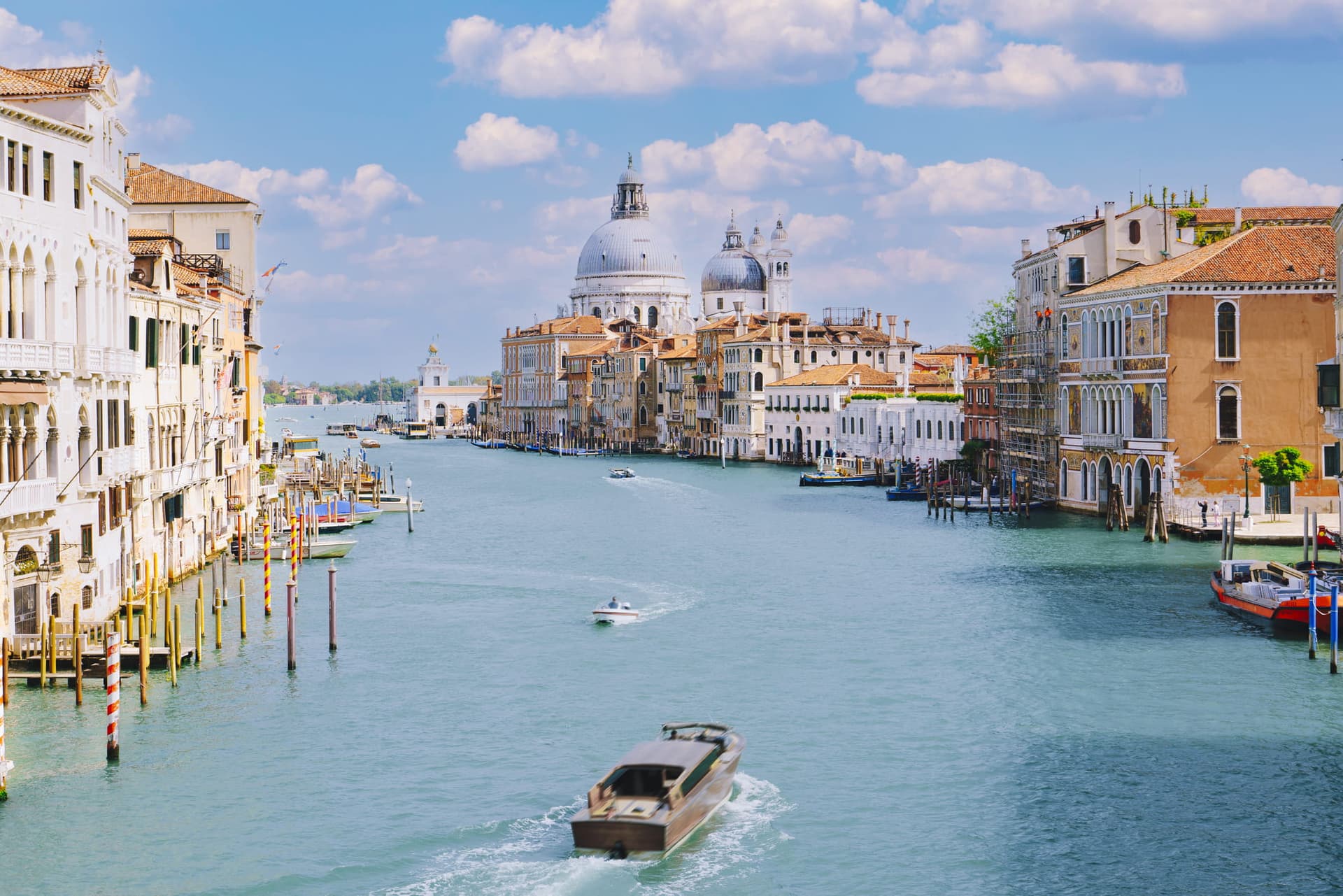 A scenic view of the Grand Canal in Venice, Italy, with historic buildings, boats, and the Basilica di Santa Maria della Salute.