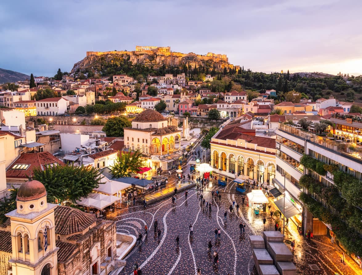 Une vue nocturne de la place Monastiraki à Athènes, avec l'Acropole en arrière-plan.