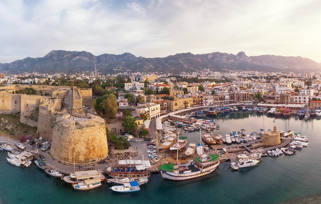 Panoramablick auf den Hafen von Kyrenia (Girne) in Nordzypern mit historischen Festungsmauern und Yachten im Wasser.