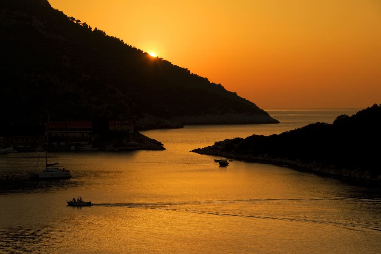 Zalazak sunca s pogledom na barku koja plovi morem i otoke Lastovskog otočja.