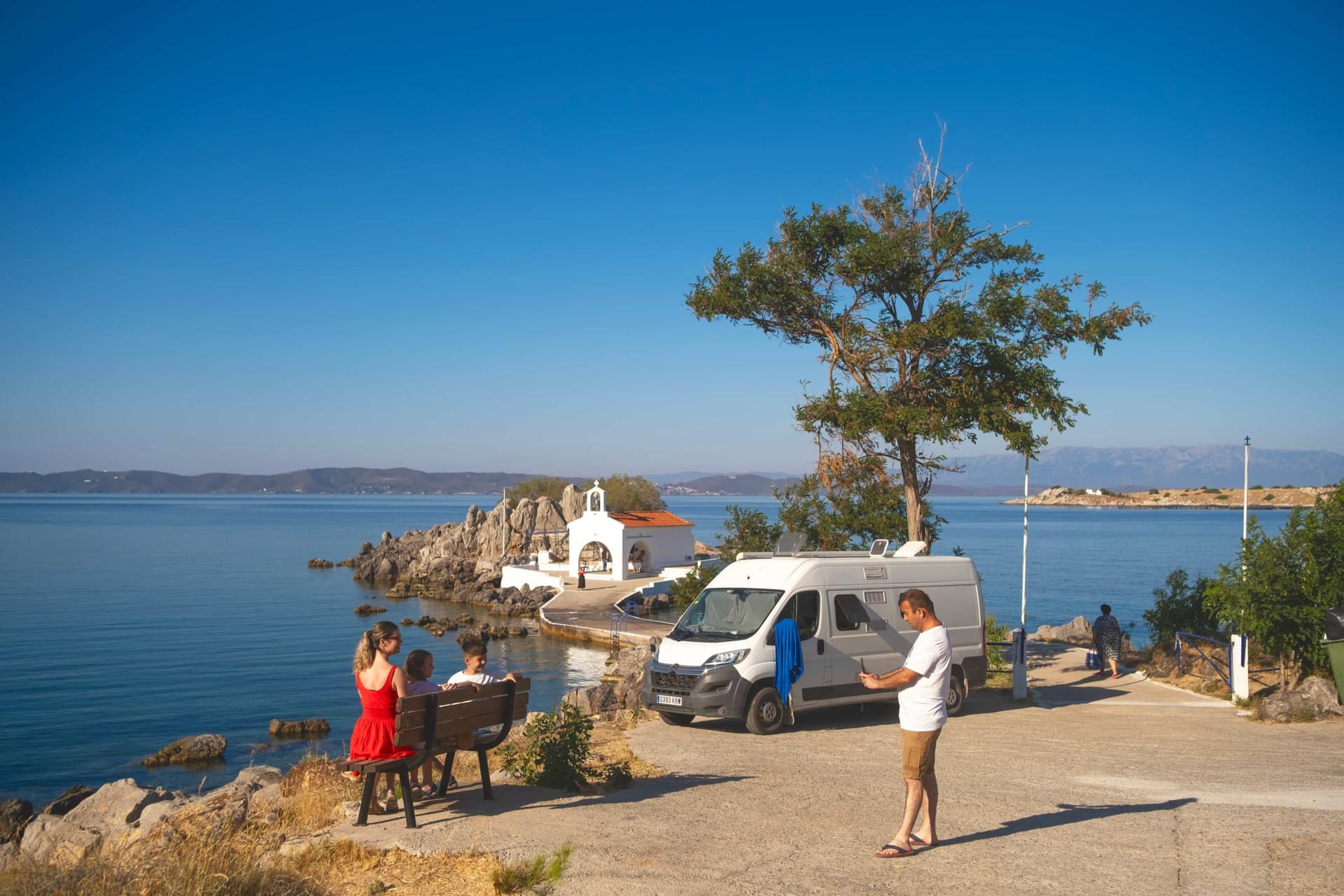 Une plage sur Chios donnant sur une petite chapelle grecque avec une famille et leur camping-car