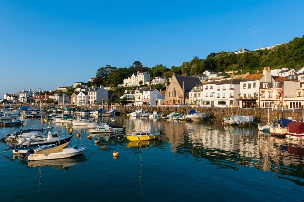 Un petit port de plaisance devant un front de mer typiquement anglais, sous un ciel bleu.